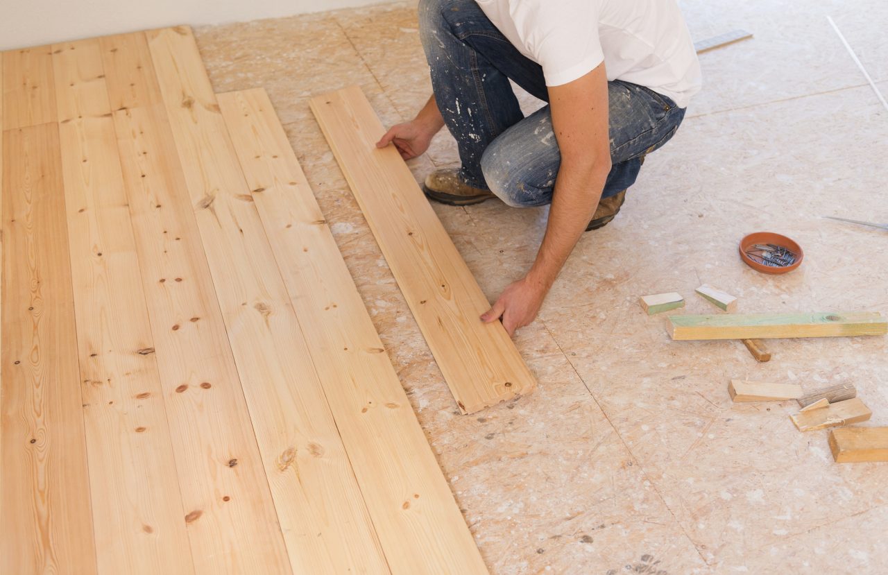 Handyman installing wooden floor in new house