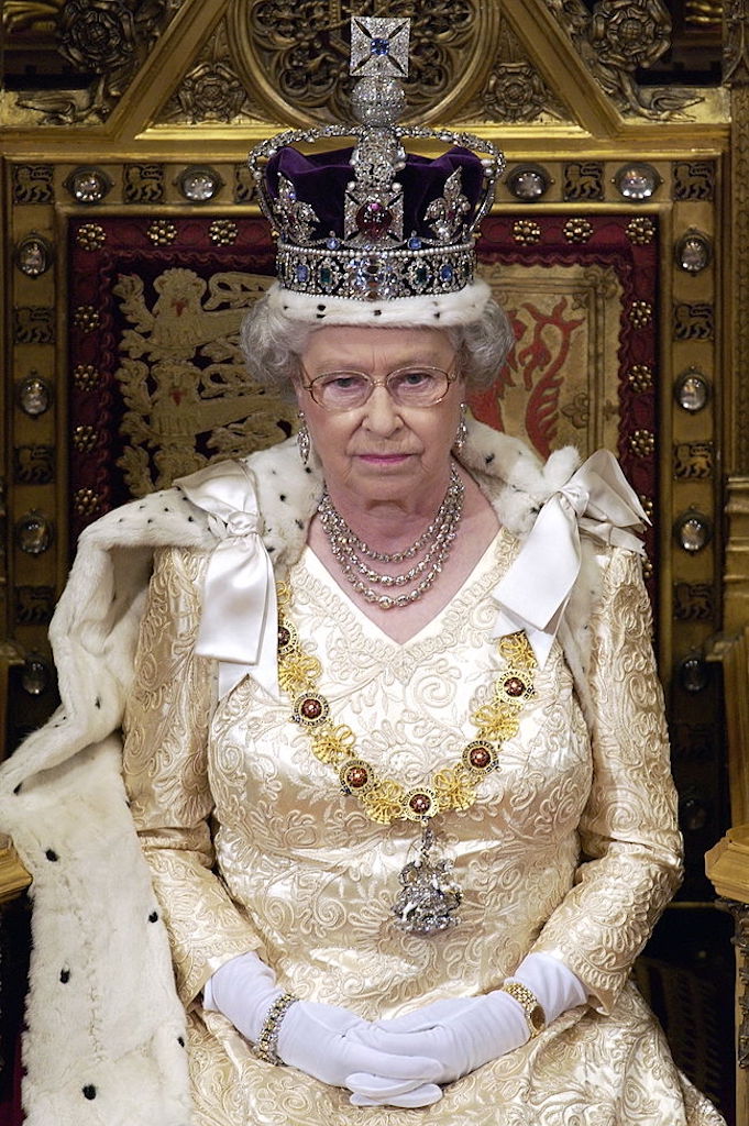 LONDON, UNITED KINGDOM - NOVEMBER 13:  Queen Elizabeth Ll Sitting On A Throne In The House Of Lords, Palace Of Westminster, Waiting To Make Her Speech During The State Opening Of Parliament.  The Queen Is Cream Satin Evening Dress Underneath Ermine-lined Robe Of State With The Imperial State Crown And The Garter Collar With A Diamond George.  (Photo by Tim Graham Photo Library via Getty Images)