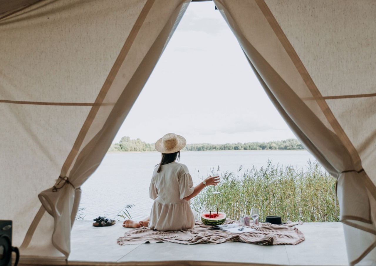 fille prend un verre de vin près de sa tente en camping