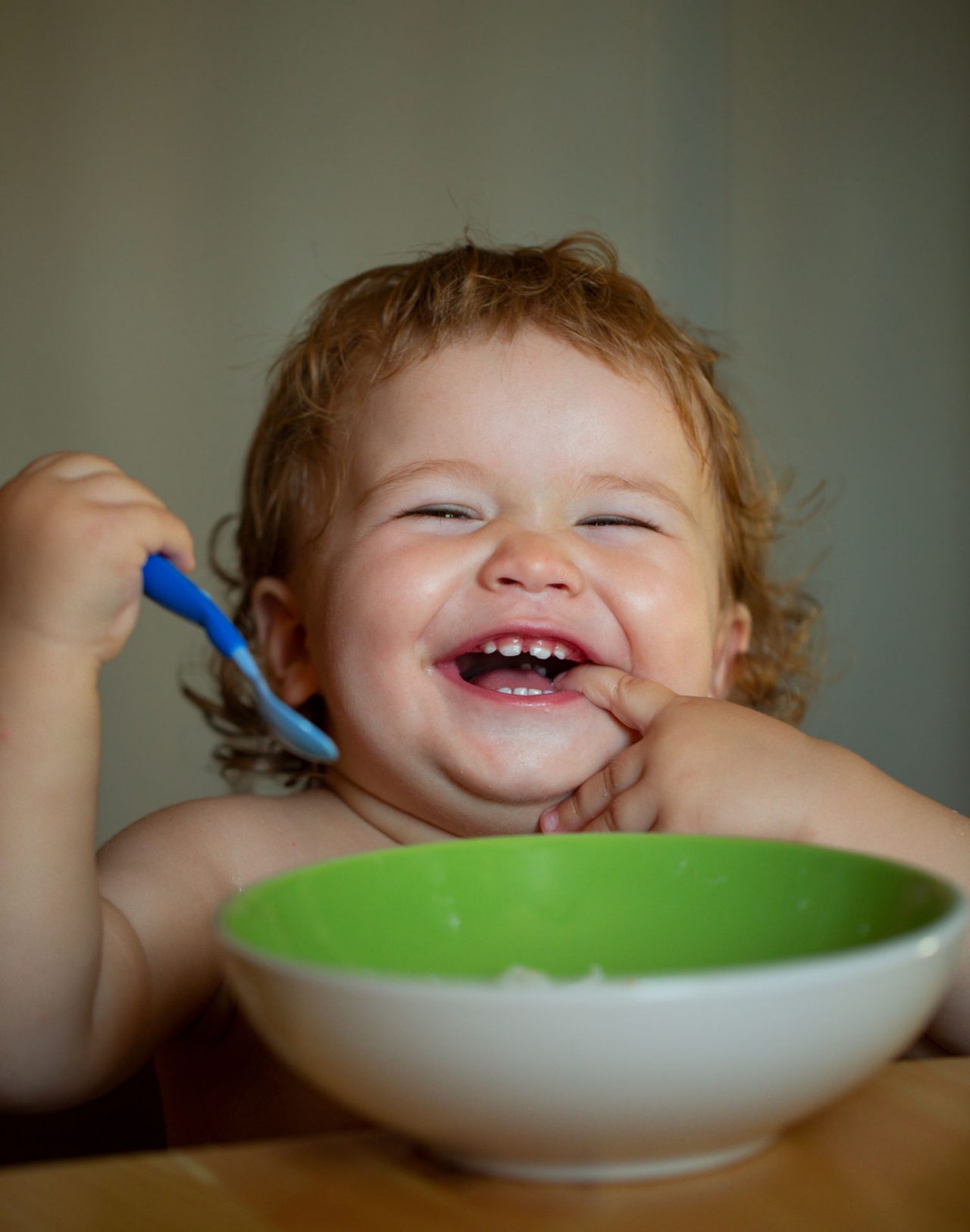 Un enfant mange seul et sourit