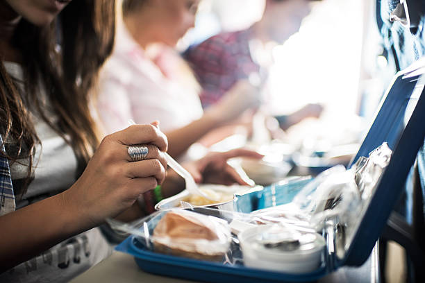 Unrecognizable people eating lunch while traveling by airplane.